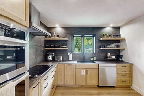Eine moderne Küche mit eingebauten Geräten, Holzschränken und einem Fenster, das natürliches Licht hereinlässt.
