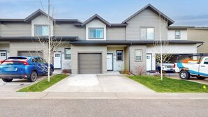 A row of two-story townhouses with attached garages, a driveway, and a small lawn area.