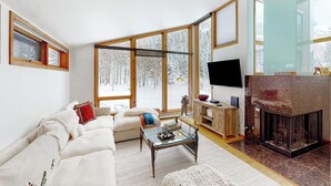 Uma sala de estar moderna com lareira, janelas amplas e um espaço de estar acolhedor.