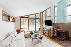 Ein modernes Wohnzimmer mit Kamin, großen Fenstern und einer gemütlichen Sitzecke.