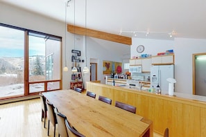 Eine moderne Küche mit Holzausbau, einer großen Kochinsel und einem Essbereich mit Holztisch und Stühlen.
