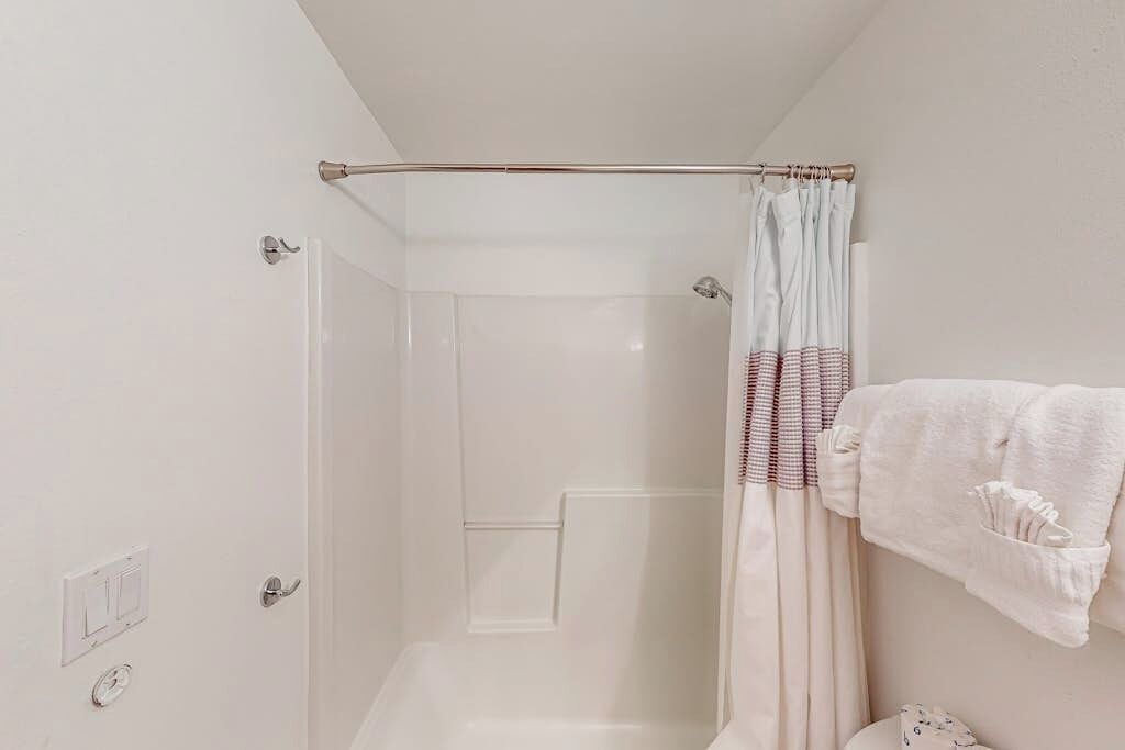 A bathroom with a shower, a towel rack, and a toilet.