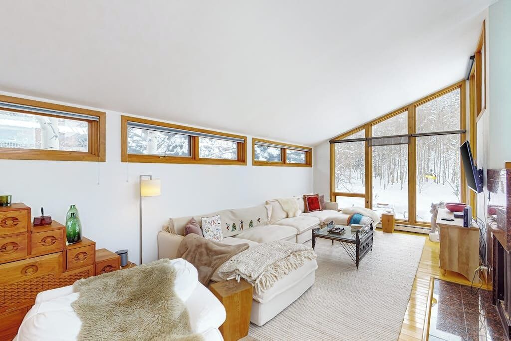 A spacious living room with a large window, a sofa, a coffee table, and a fireplace.