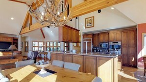Une cuisine spacieuse dotée de meubles en bois, d’un îlot central et d’un coin repas avec une table et des chaises en bois.