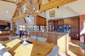 A spacious kitchen with wooden cabinets, a central island, and a dining area with a wooden table and chairs. - Luxury Home with Upscale Fixtures, WiFi, Private Hot Tub, & Mountain Views (Silverthorne)