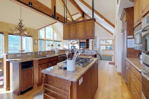 A spacious kitchen with wooden cabinets, a granite countertop, and a large island. - Luxury Home with Upscale Fixtures, WiFi, Private Hot Tub, & Mountain Views (Silverthorne)