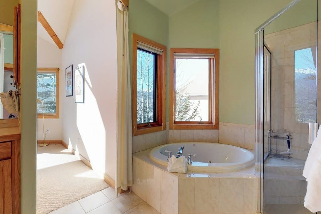 A bathroom with a large bathtub, a shower, and a window providing natural light.