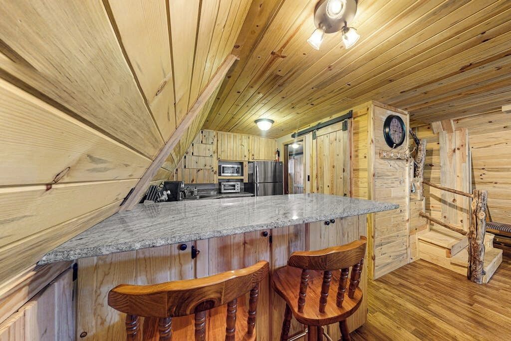 L’intérieur d’un chalet en bois comprend une cuisine, un coin bar et une horloge murale.