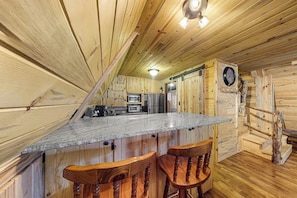 Ein Holzblockhaus-Interieur mit Küche, Bar und einer Uhr an der Wand.