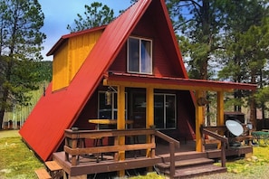 Eine rote und gelbe Holzhütte mit Veranda, Satellitenschüssel und einer Holzterrasse.