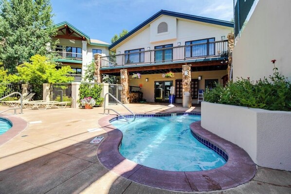 A hotel with a swimming pool, a covered patio, and a two-story building with balconies. - Ski-in/Ski-Out, Outdoor Pool, Hot Tub, Tennis, Sauna, & Gym (Steamboat Springs)