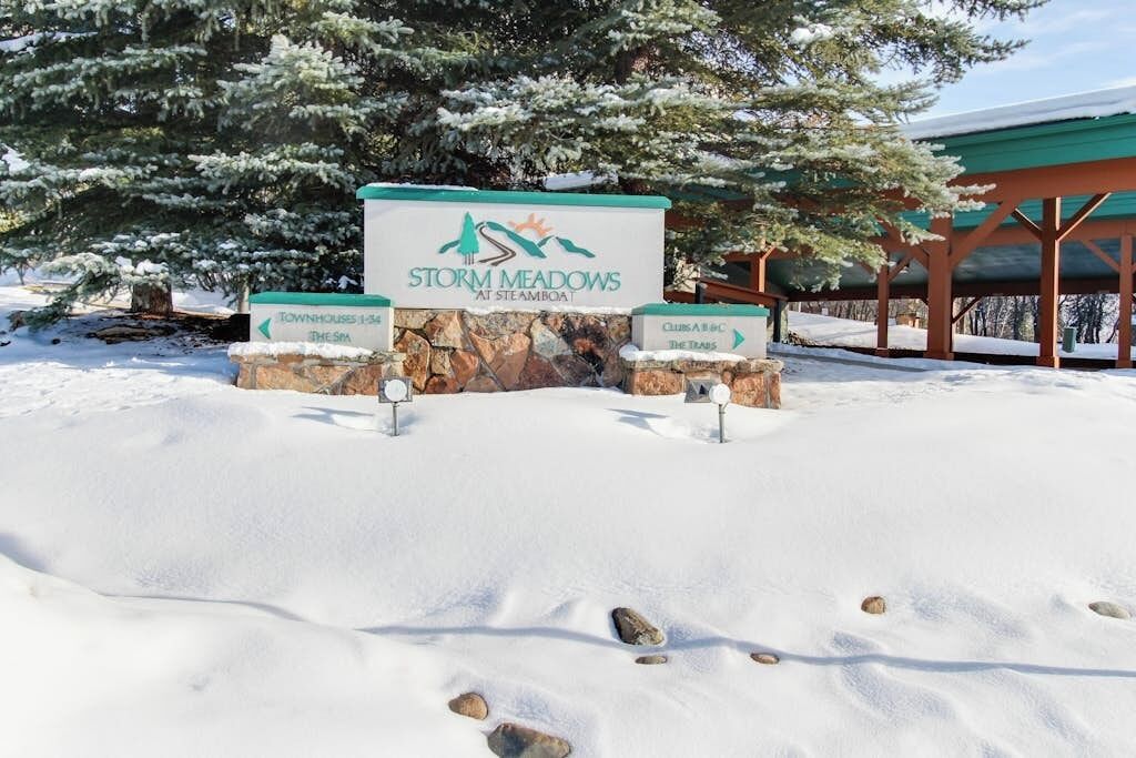 A snow-covered sign for Storm Meadows at Steamboat with directional arrows to townhouses and the spa.