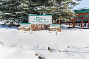 A snow-covered sign for Storm Meadows at Steamboat with directional arrows to townhouses and the spa. - Ski-in/Ski-Out, Outdoor Pool, Hot Tub, Tennis, Sauna, & Gym (Steamboat Springs)