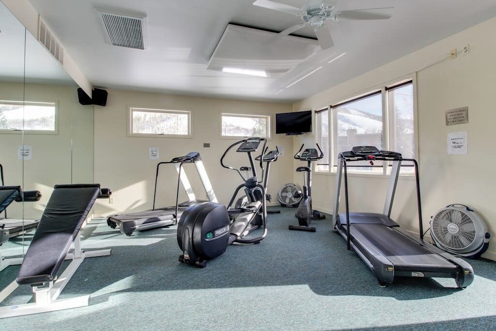 Un gimnasio con equipo de ejercicio, una caminadora y un ventilador.