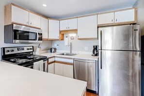 A modern kitchen with stainless steel appliances, white cabinetry, and a dishwasher. - Ski-in/Ski-Out, Outdoor Pool, Hot Tub, Tennis, Sauna, & Gym (Steamboat Springs)