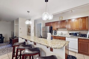 Eine Küche mit Granit Arbeitsplatten, Holzschränken, einem Kühlschrank, einer Mikrowelle und einem Geschirrspüler.