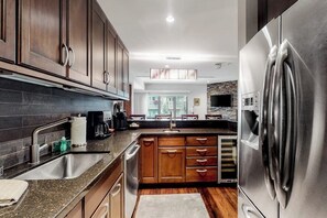 Eine moderne Küche mit dunklen Holzschränken, Edelstahlgeräten und einem großen Kühlschrank.