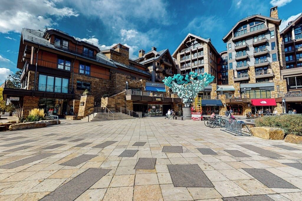 Un hotel con fachada de piedra, varios pisos y un patio central con una escultura decorativa.