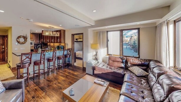 A spacious living area with a leather sofa, a coffee table, and a kitchen in the background. - 1 Block to Vail Mountain! Village Condo w/ Fireplace, Great Views & Shared Pool (Vail)