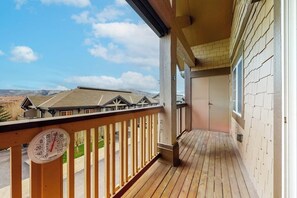Eine Holzterrasse mit Thermometer, Blick auf Häuser und klarem Himmel.