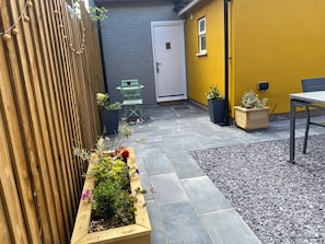 A patio with a wooden fence, a door, a small table, and potted plants. - Three en-suite bedroom bungalow centrally located (Craven Arms)