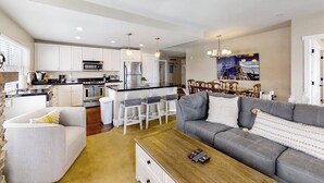 A modern kitchen with white cabinets, a central island, and bar stools. - Family-friendly condo w/mountain & valley views, WiFi, shared pool, hot tub (Granby)
