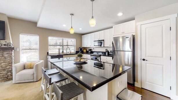 A modern kitchen with a central island, stainless steel appliances, and a seating area with bar stools. - Family-friendly condo w/mountain & valley views, WiFi, shared pool, hot tub (Granby)