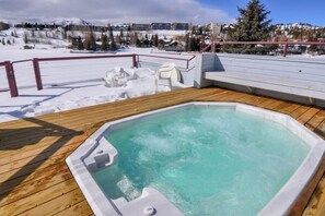 Ein Whirlpool auf einer Holzterrasse mit verschneiter Landschaft im Hintergrund.