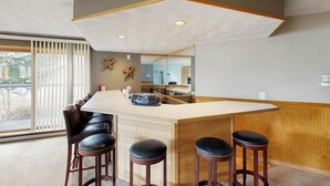 Una cocina moderna con una isla central, taburetes de bar y un amplio ventanal.