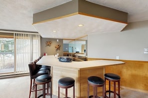 A modern kitchen with a central island, bar stools, and a large window. - Lakefront retreat with mountain views, covered parking & updated interiors (Dillon)