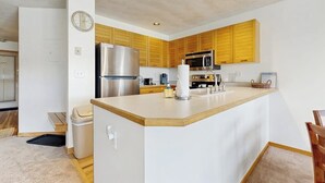 Una cocina moderna con armarios de madera, un refrigerador de acero inoxidable, un microondas y un fregadero.
