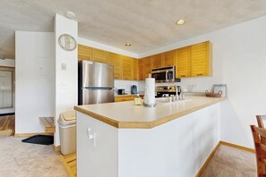 A modern kitchen with wooden cabinets, a stainless steel refrigerator, a microwave, and a sink. - Lakefront retreat with mountain views, covered parking & updated interiors (Dillon)