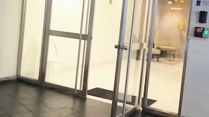 A hotel entrance with a glass door, a reception desk, and a visible room number. - Central Suite (Lima)
