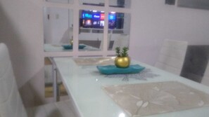 Un comedor con una mesa blanca, un adorno dorado y un cojín azul.
