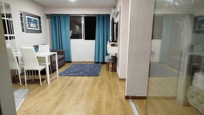 A modern living room with a dining area, a sofa, a TV, and a glass partition. - Central Suite (Lima)