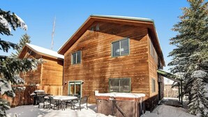 Eine Holzhütte mit Terrasse, Whirlpool und überdachter Sitzgelegenheit im Freien.
