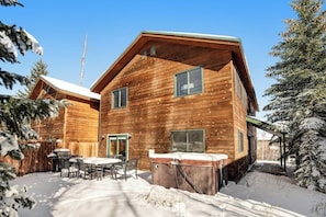 Eine Holzhütte mit Terrasse, Whirlpool und überdachter Sitzgelegenheit im Freien.