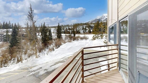Un balcon avec vue sur des montagnes et des arbres couverts de neige.