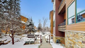 A snow-covered pathway leading to a building with a stone facade and large windows. - Kutuk 108 Ski, stay, & play - Steamboat Springs getaway only steps away from the mountain (Steamboat Springs)