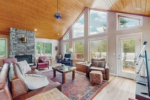 A spacious living room with a stone fireplace, large windows, and a wooden ceiling. - Secluded Mountain Cabin w/ Hot Tub, Fireplace & Stargazing Deck near Breck (Alma)