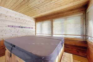 Ein Holzblock-Innenraum mit Sauna, Holzwänden und einem Fenster mit Jalousien.