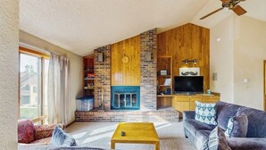 Ein Wohnzimmer mit Kamin, Fernseher und Deckenventilator.
