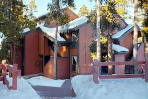 Eine hölzerne Hütte mit schneebedecktem Dach, umgeben von Bäumen.
