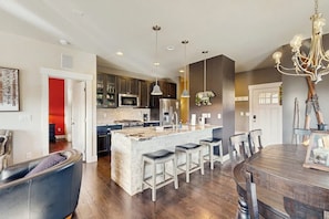 A modern kitchen with a central island, bar stools, and a dining table with chairs. - Modern townhome w/ mountain views, 2 outdoor spaces, & a gas grill (Fraser)