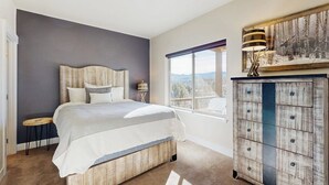 Een slaapkamer met een bed, een dressoir, een raam met uitzicht en een plafondlamp.