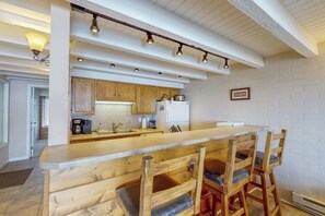 Eine Küche mit Holzausstattung, einem weißen Kühlschrank und einer Bar mit Holzstühlen.