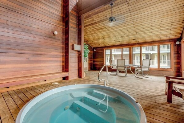Ein Holzblock-Interieur mit Whirlpool, Holzböden und einem Balkon mit Sitzgelegenheit.