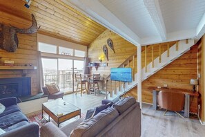 Ein gemütliches Wohnzimmer mit Kamin, Treppe und Fernseher.