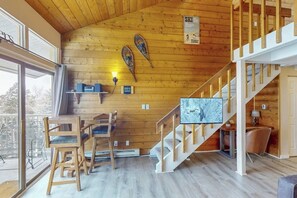 Ein Holzinnenraum mit Essbereich, einer Treppe und einem an der Wand befestigten Fernseher.