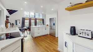 Une cuisine moderne dotée d’un îlot central, d’un coin repas avec une table et des chaises, et d’un four encastré.
